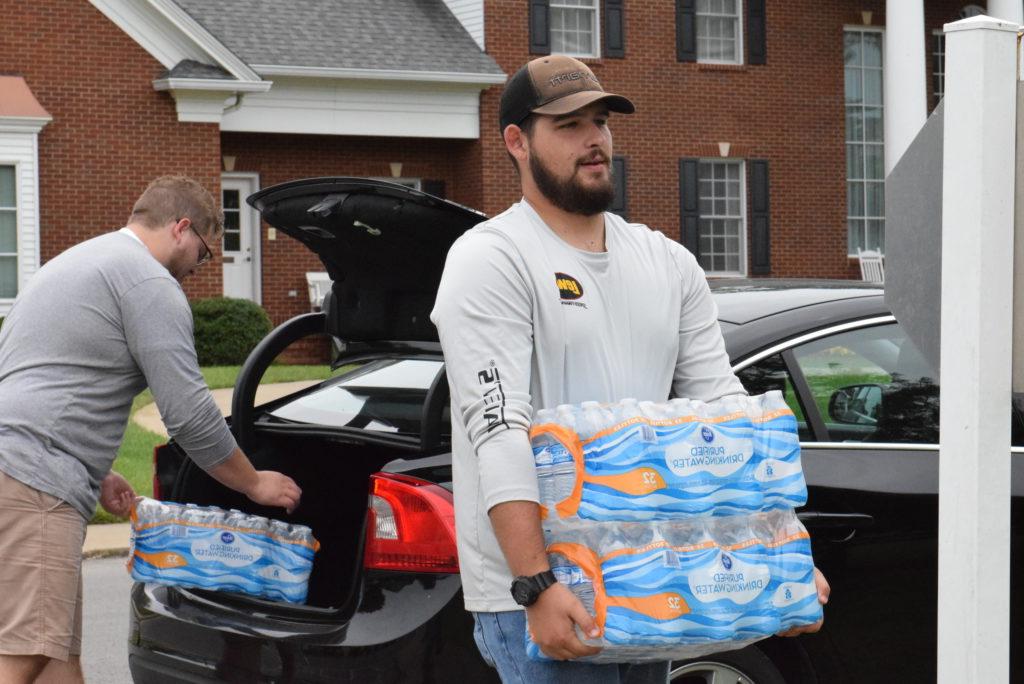 Adam Carmen and Lucas Humphrey carry cases of water to Stapp Lawn for hurricane relief donation. (CU photo by Andrea Burnside)